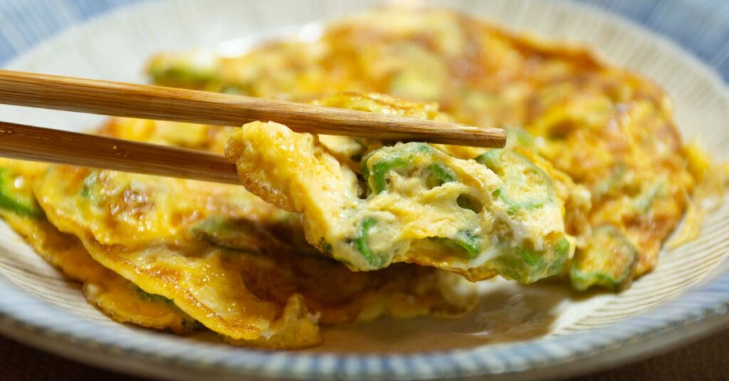Close-up of a Japanese omelette served with chopsticks, showcasing vibrant colors and texture.